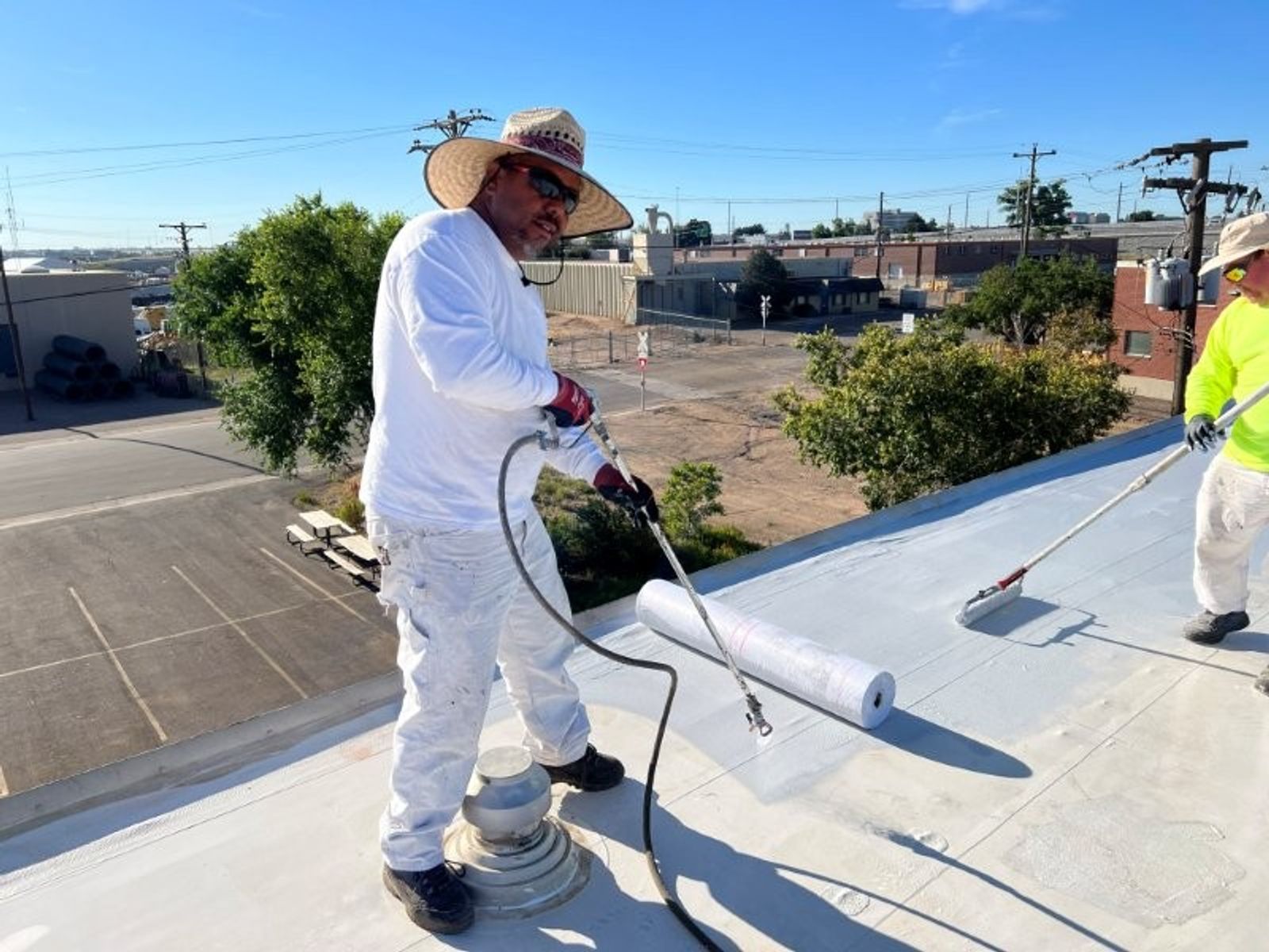 Commercial roof mid-overlay with white surface work in progress across a large low-slope deck.