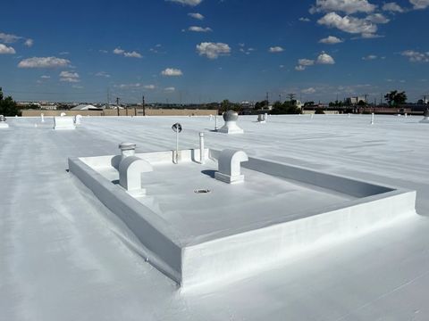 Completed bright white overlay surface on a flat commercial roof with vents and a clear horizon.