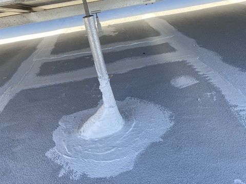 Close view of sealed seams and coated flashings on a commercial roof under solar racking.