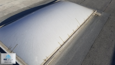 Person walking a commercial roof during an inspection, photographing membrane and equipment areas.